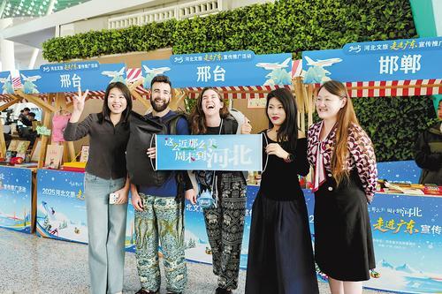 11月24日，在广州白云国际机场，外国游客在河北文旅主题市集前合影留念。