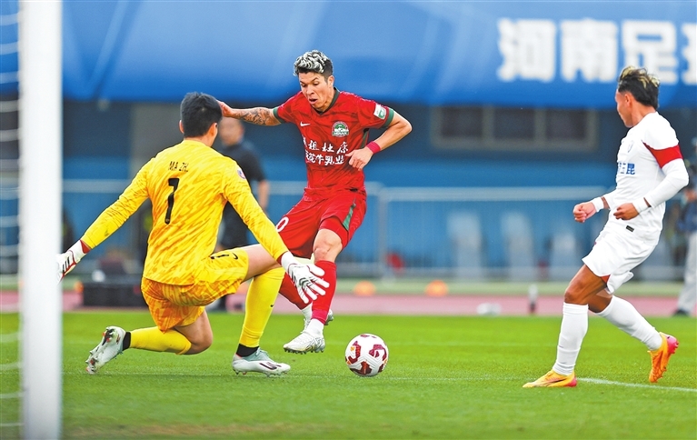 河南队球员纳萨里奥（中）与云南玉昆队守门员马镇（左）在比赛中拼抢。 新华社发