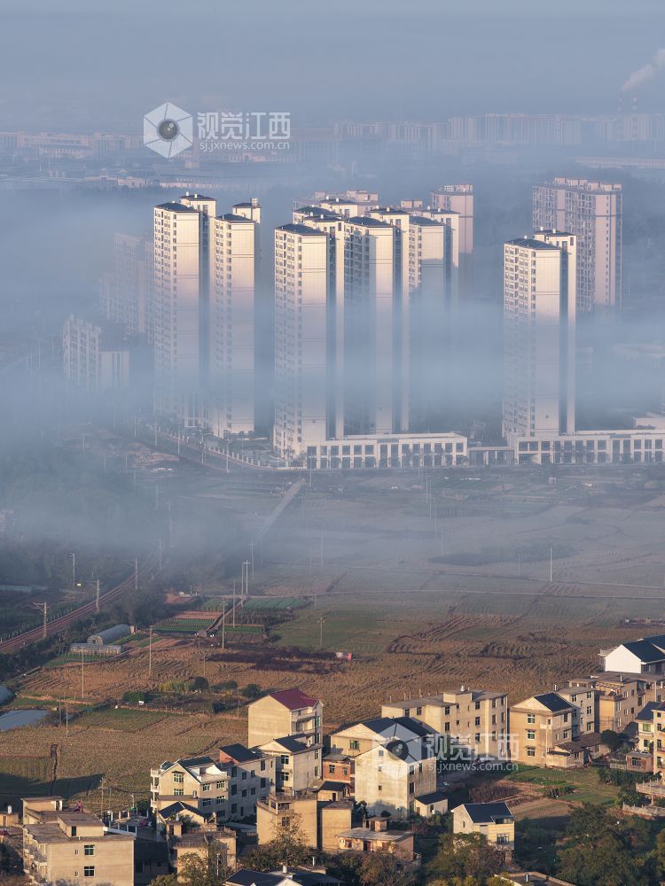 2025年11月24日,航拍江西省上饶市铅山县城乡晨雾如纱,轻柔地缠绕着城市楼宇与乡村民居,城市建筑与错落的村落相映成趣。