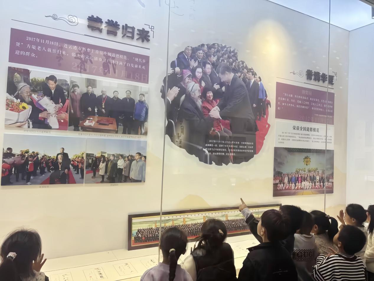 (图为孩子们驻足观看楷模图文介绍。郭琳琳摄)