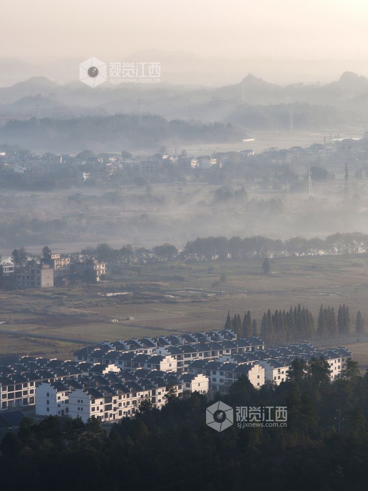2025年11月24日,航拍江西省上饶市铅山县城乡晨雾如纱,轻柔地缠绕着城市楼宇与乡村民居,城市建筑与错落的村落相映成趣。