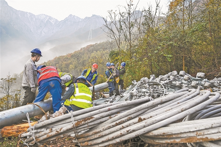 11月20日，茂县富顺镇境内，工人们在塔下组装电力设备。