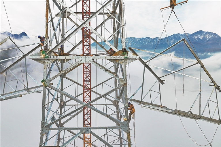 11月20日，四川省阿坝藏族羌族自治州茂县富顺镇境内，绵延的高山之巅云遮雾绕，工人们爬上高塔进行组塔作业。