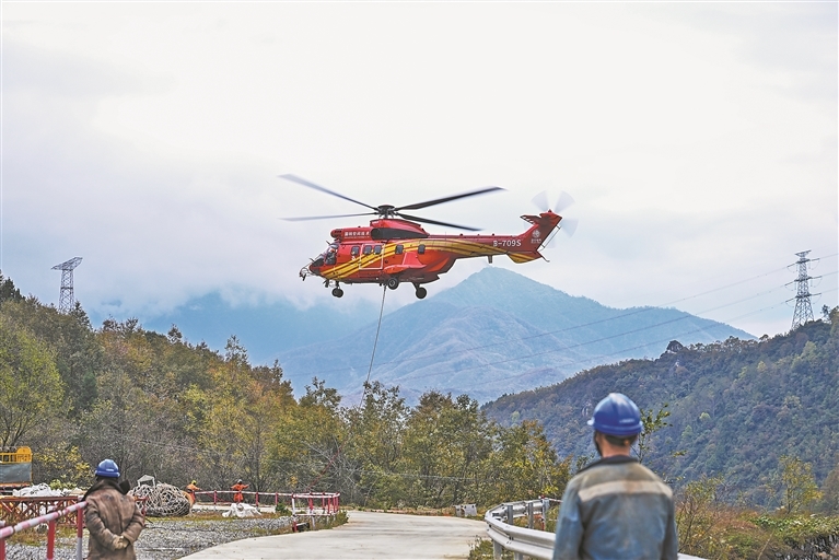 11月18日，在茂县土门镇境内，一架直升机在空中来回穿梭，将铁塔建材一趟趟地运往施工点。