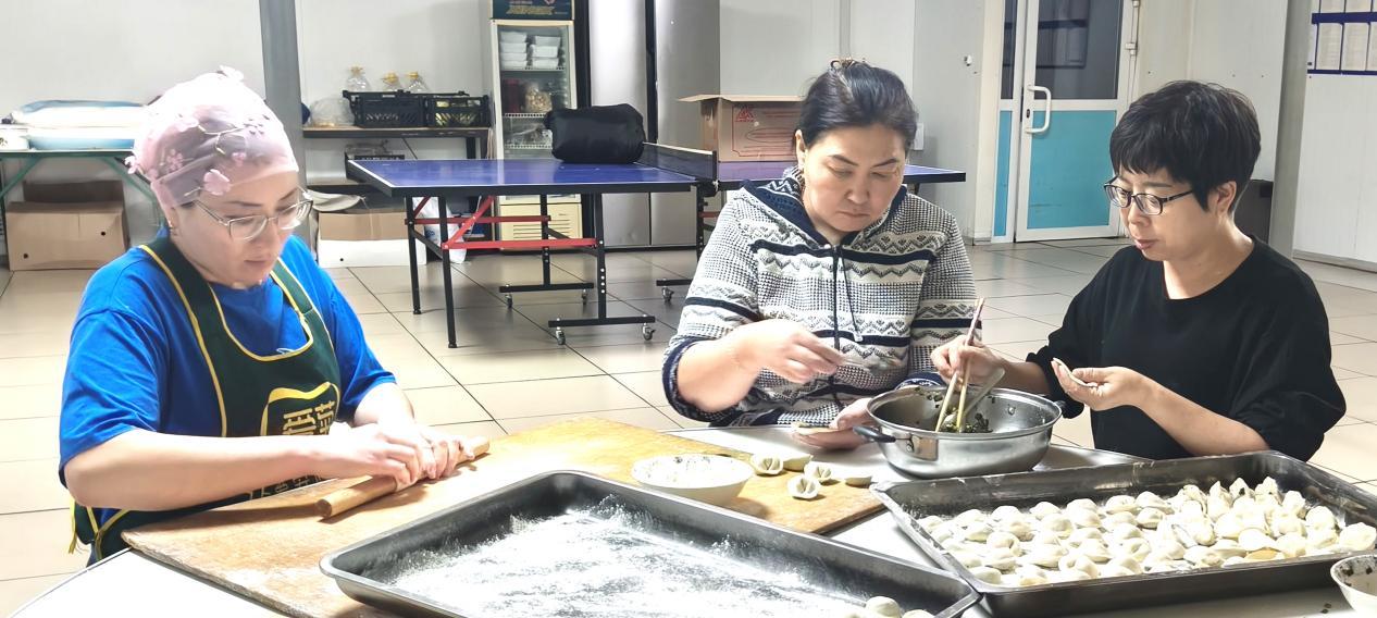 图为爱菊哈萨克斯坦园区员工阿依古丽(左一)正在和中国员工学习饺子包法。西安爱菊粮油工业集团供图