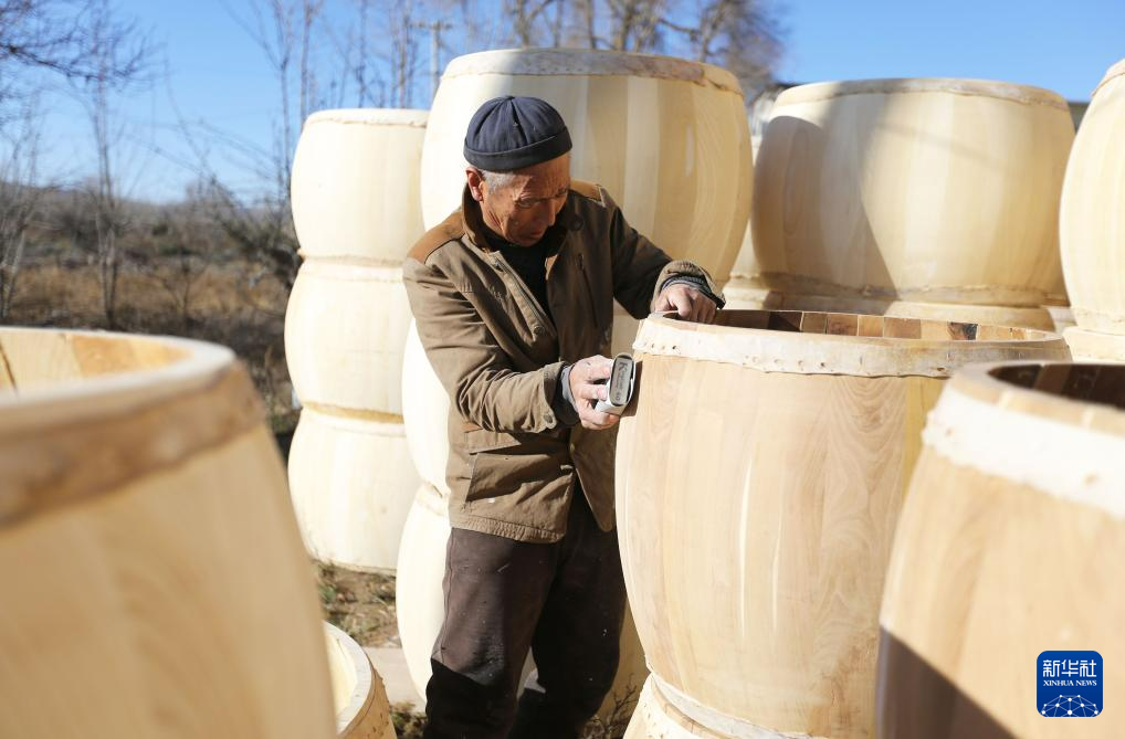 11月27日，手工艺人周天成打磨牛皮鼓。新华社发（王克贤　摄）