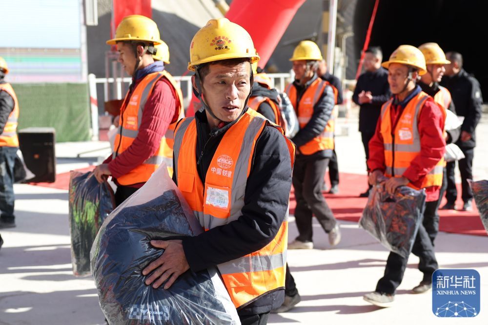 ↑12月2日,参与隧道建设的中铁二十局建设者在施工一线领取到御寒保暖的棉服。