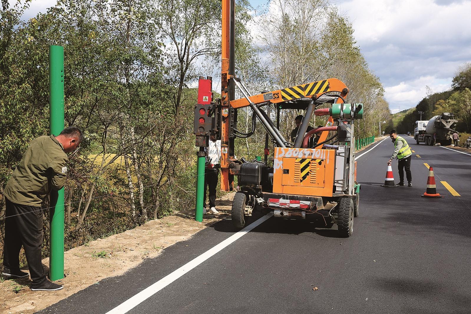 施工人员正忙着为新修的公路安装安全设施。