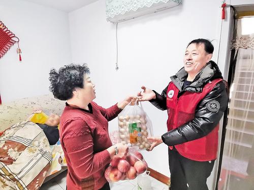 12月1日,秦皇岛市首府社区志愿者胡秀军(右)为居民配送物品。