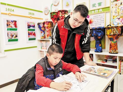 11月28日,在秦皇岛市工人南里第二社区“小候鸟驿站”,大学生志愿者正为一名孩子辅导功课。