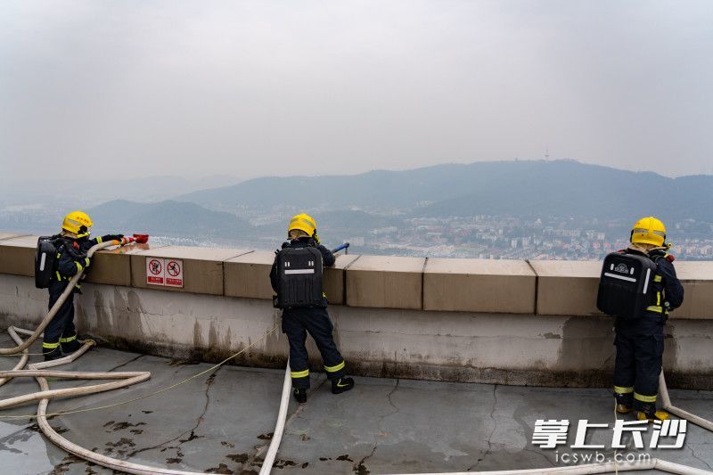 消防员运用屏风水枪等为玻璃幕墙降温。
