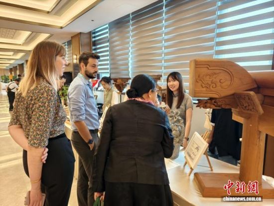 戈玉兰(右一)向海外参观者介绍江南传统古建的构件。　受访者供图