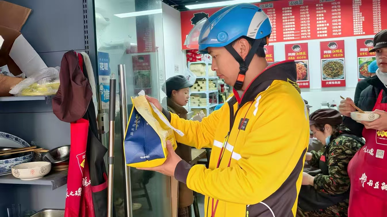 ▲康居西城公租房居民邹新正在取餐。