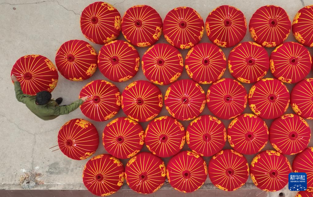 12月10日,工人在河北省石家庄市藁城区屯头村一家宫灯厂晾晒制作好的宫灯(无人机照片)。