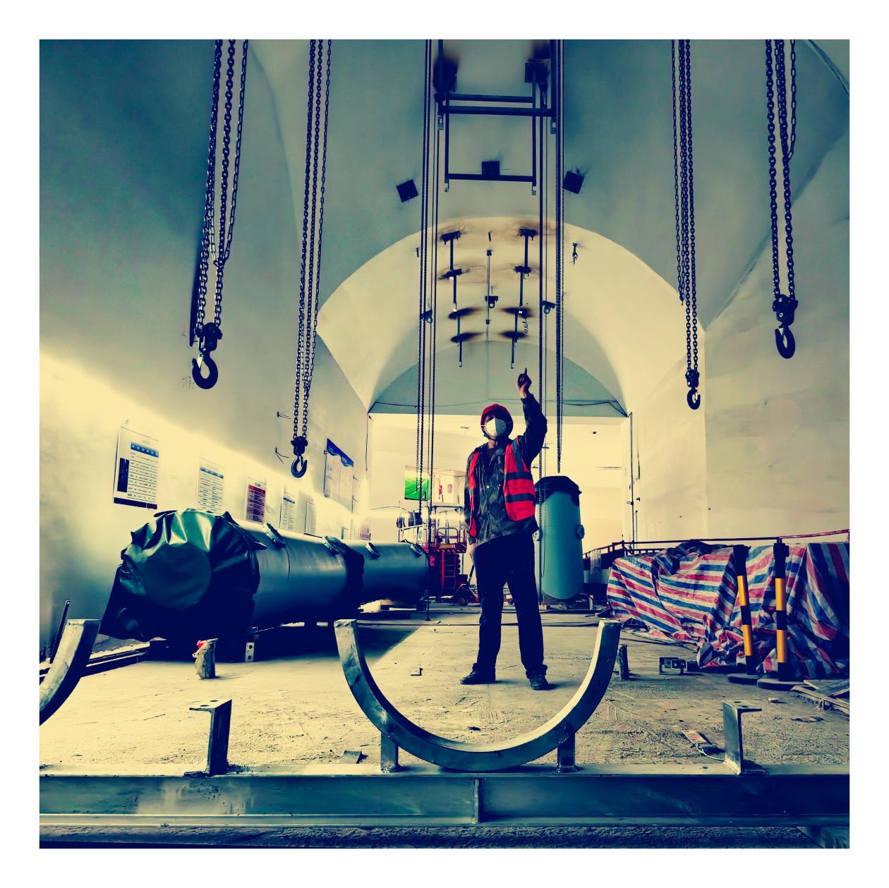 鲁山豫能抽水蓄能电站地下厂房内，建设者精准指挥机组吊装作业，勾勒出能源工程建设的动人剪影。摄影：李运明