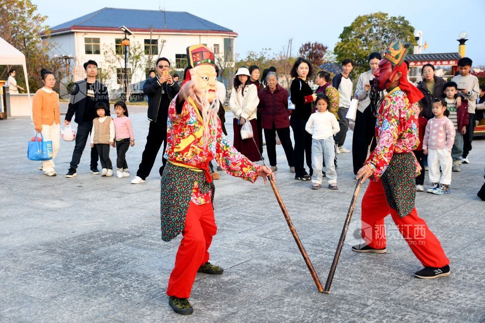 2025年12月7日下午,江西省抚州市南丰县蜜桔湖景区橘子餐厅广场,傩师们在跳傩祈福,吸引省内外游客们驻足观看、拍照,游客们还拿着傩面具拍照留念。