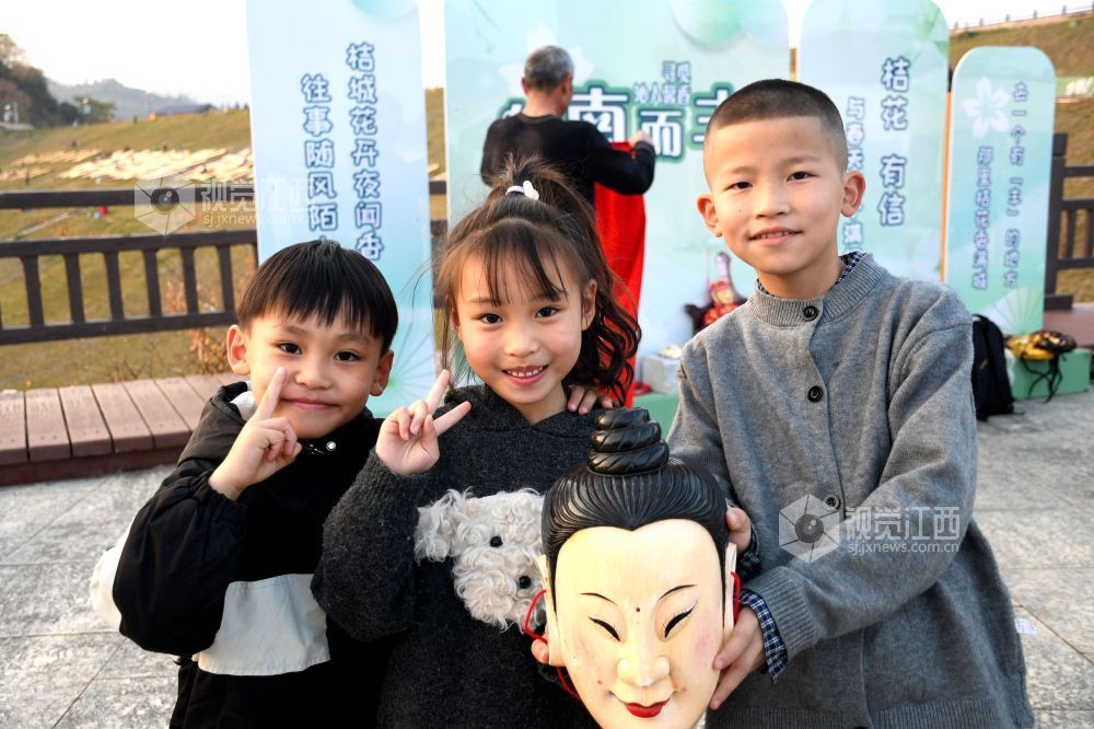 2025年12月7日下午,江西省抚州市南丰县蜜桔湖景区橘子餐厅广场,傩师们在跳傩祈福,吸引省内外游客们驻足观看、拍照,游客们还拿着傩面具拍照留念。