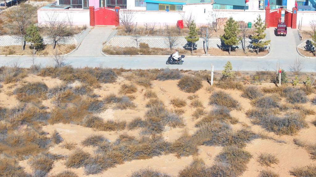 12月4日，张万泰骑车经过移民新村。新华社发