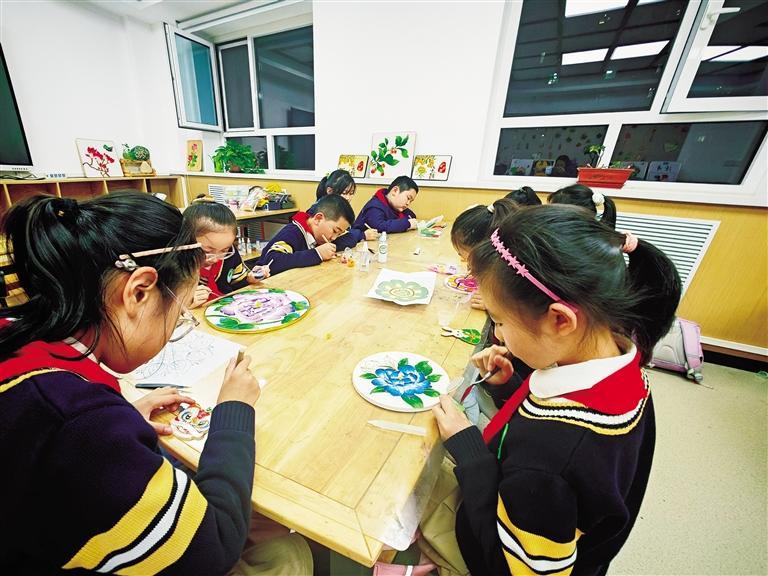 金塔路小学的掐丝珐琅社团内，孩子们进行填砂。