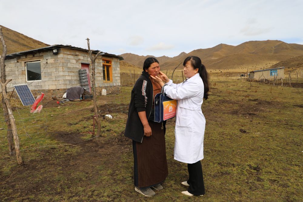 王蒋艳在屋外为牧民索南草检查伤口　新华社记者　梁军　摄