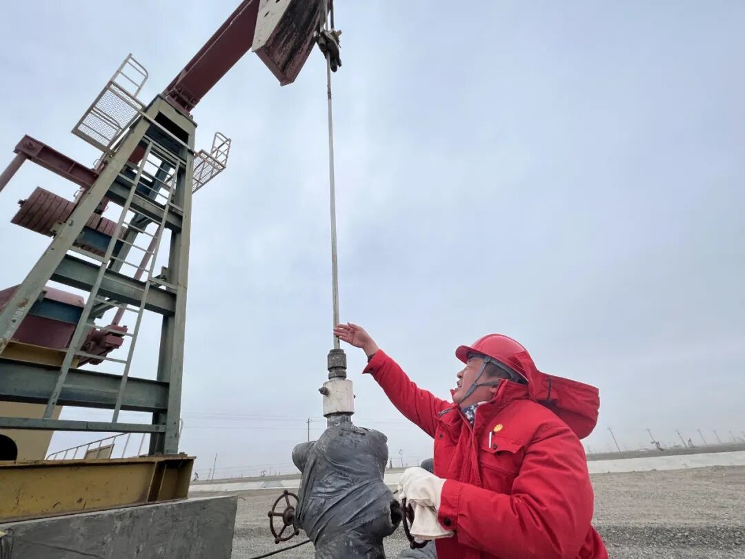 图为巡检职工在井场检查油井运行情况（通讯员：孙廷勇/摄）