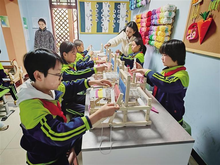 伏龙坪小学的编织非遗工坊内，孩子们用简易织布机织布。