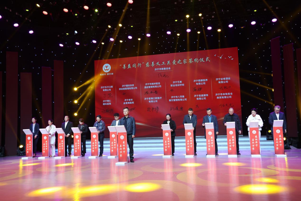 济宁市慈善总会副会长任亮（中）与12家爱心企业代表签署“善益同行”慈善义工关爱之家合作协议
