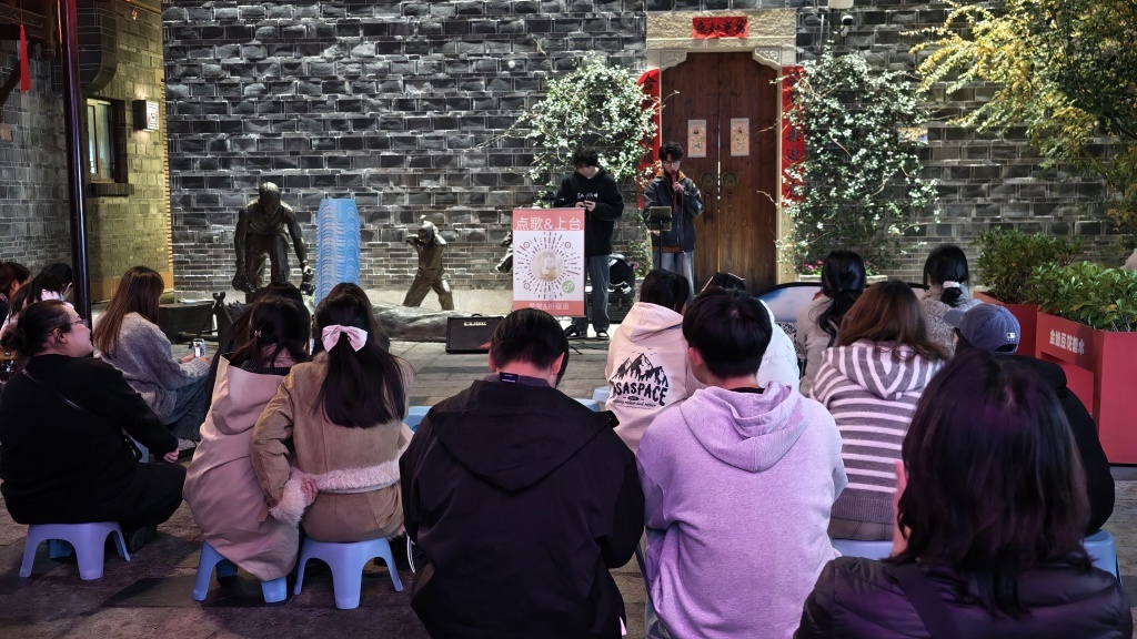 12月11日晚，一群年轻游客在万寿宫街区听路边演唱。万寿宫有多个路边演唱表演点位，成为年轻人放松心灵的好去处。 澎湃新闻记者 王洛伊 图