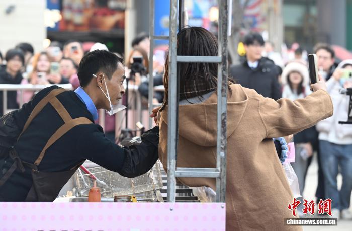 12月12日，“鸡排哥”李俊永和市民合影。当日，江西景德镇网红“鸡排哥”李俊永全国巡炸之旅来到浙江杭州，当地民众排起百米长队品尝。中新社记者 王刚 摄