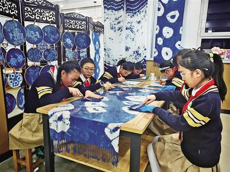 金塔路小学的扎染非遗社团内，孩子们进行扎染纹样设计和清洗处理。