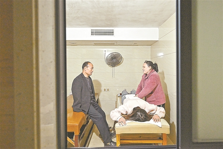 在万载县城一家推拿店，周毛根上门回访自己推荐就业的残疾人。特约通讯员 邓龙华摄