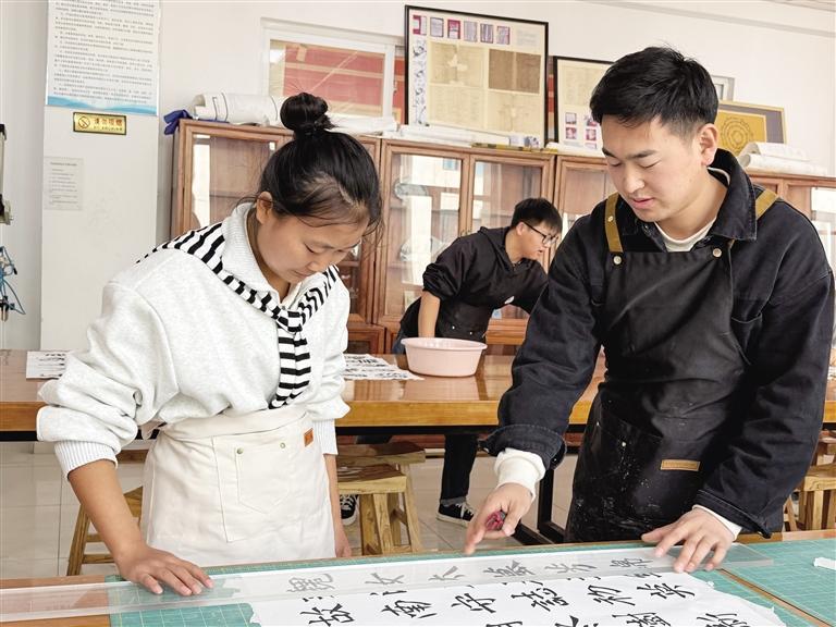 兰州职业技术学院古籍修复大师工作坊内，老师指导学生进行书画装裱。刘宝丽　摄