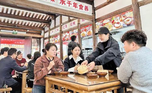 12月8日，在位于福建省三明市沙县区东门古街的沙县小吃小食堂内，服务员正为顾客端上黄精牛肉蒸饺。 本报记者 徐华摄