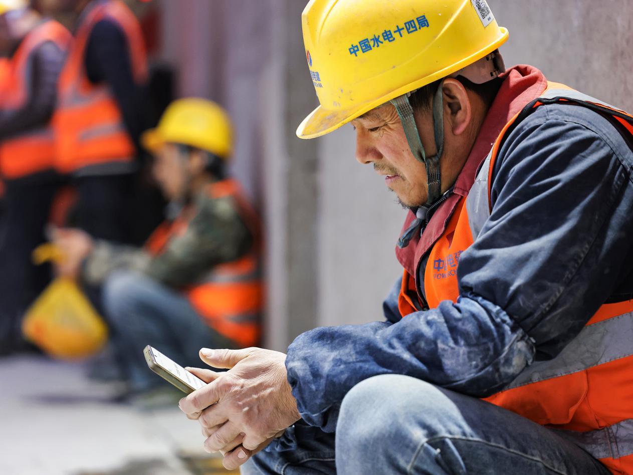 建设者利用午休时间，给家人发个微信，报一下平安。摄影：郭东伟