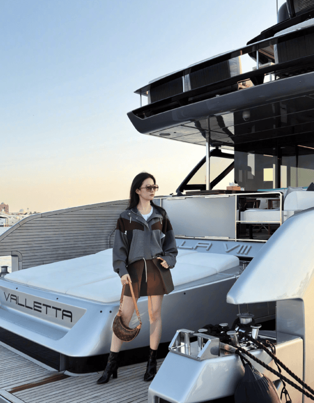 刘亦菲戴着墨镜在船头摆姿势拍照。