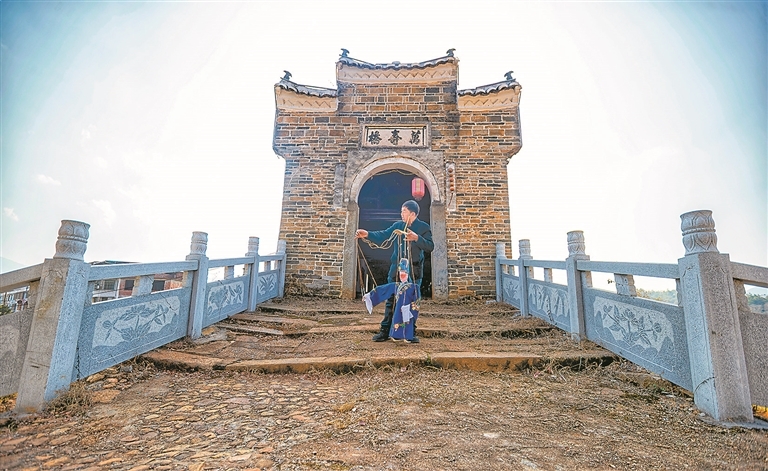 谢帮银在塘坊镇万寿桥上练习木偶戏的唱词和指法。