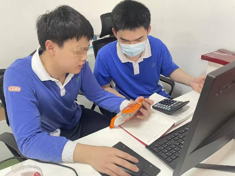 图为文文和搭档在将商品价格录入电脑扫码系统
