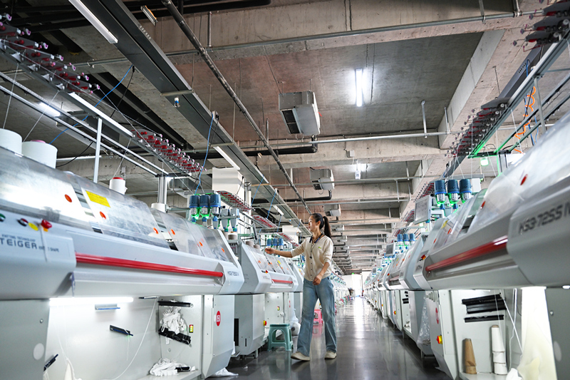 11月25日,在清河国际羊绒高端针织产业园数字化共享工厂,工人利用全自动电脑针织横机生产羊绒服饰产品。