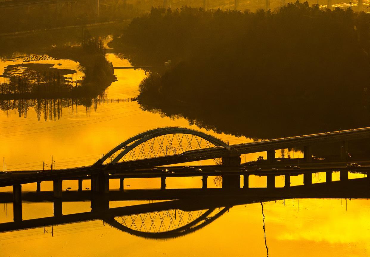 12月16日,一列动车从东湖湖面上空驶过(无人机照片)。新华社记者 肖艺九 摄
