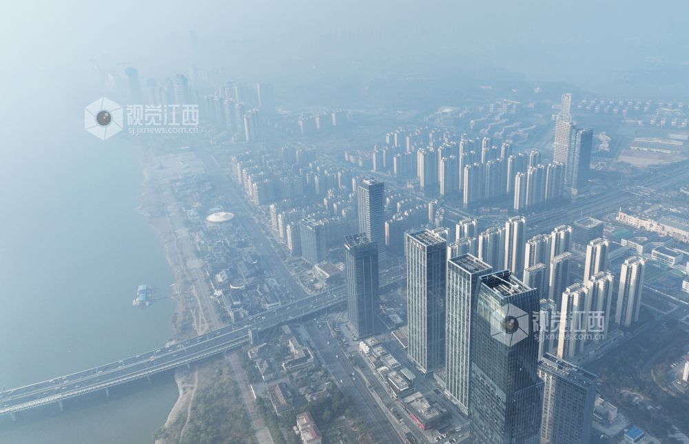 12月19日上午，航拍镜头中的南昌赣江两岸，高层建筑在雾霾中若隐若现。