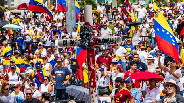 ▎2024年8月3日,委内瑞拉人在迈阿密市中心举行抗议活动时,展示了一座由 PVC 管制成、印有“不要再有共产主义”口号的十字架。(图源:迈阿密先驱报)