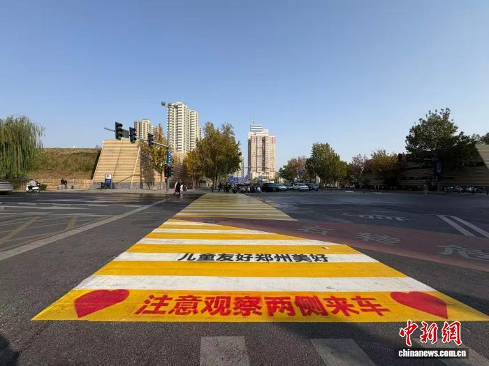 图为上学高峰时段学校安全员护送学生穿行彩色斑马线。　张楠 摄