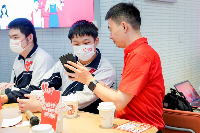 图为文文参加院外职业体验活动与天使餐厅的天使店员互动