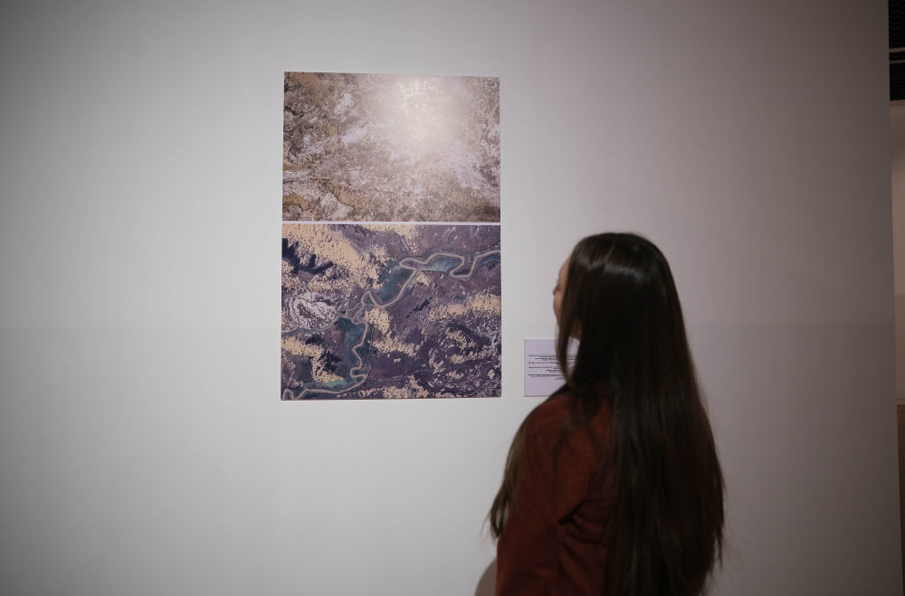 12月10日，在哈萨克斯坦阿斯塔纳的国家博物馆，参观者在图片展上观赏新疆塔里木河畔治沙工程的拼版对比照片。