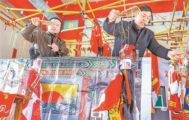 12月9日，广昌县塘坊镇大株村，省级非物质文化遗产塘坊木偶戏代表性传承人谢帮银（右）和剧团成员在表演木偶戏经典剧目《文王访贤》。