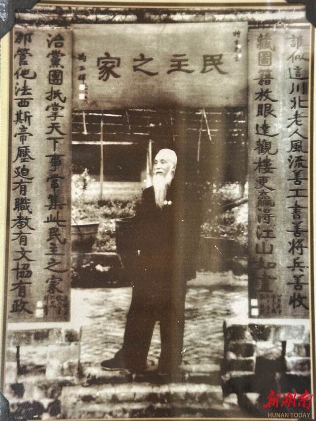 1953年，鲜英在特园留影，身后楹联为其手书。（资料图片）