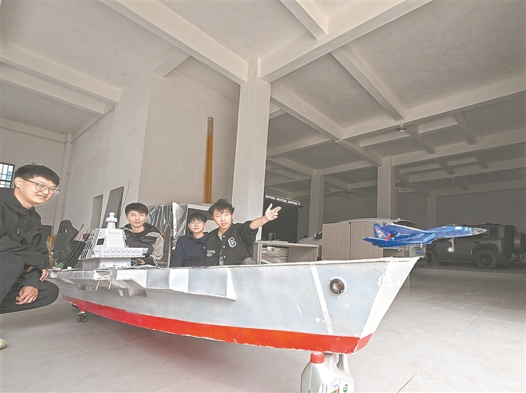 11月11日，赣州市南康区龙华镇一间工作室内，刘祥强（左二）和团队成员在福建舰模型上弹射起飞舰载机航模。