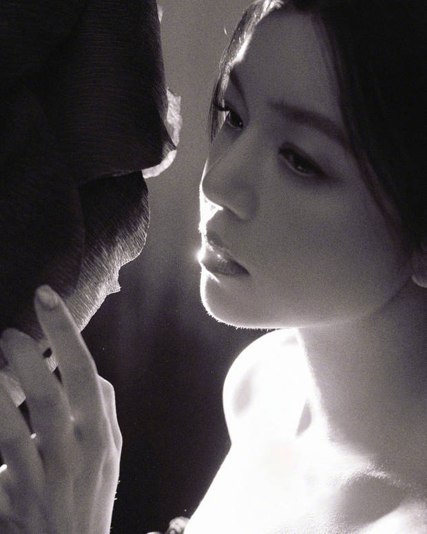 陈妍希抬手轻触巨型黑玫瑰，黑色抹胸裙贴合身形。