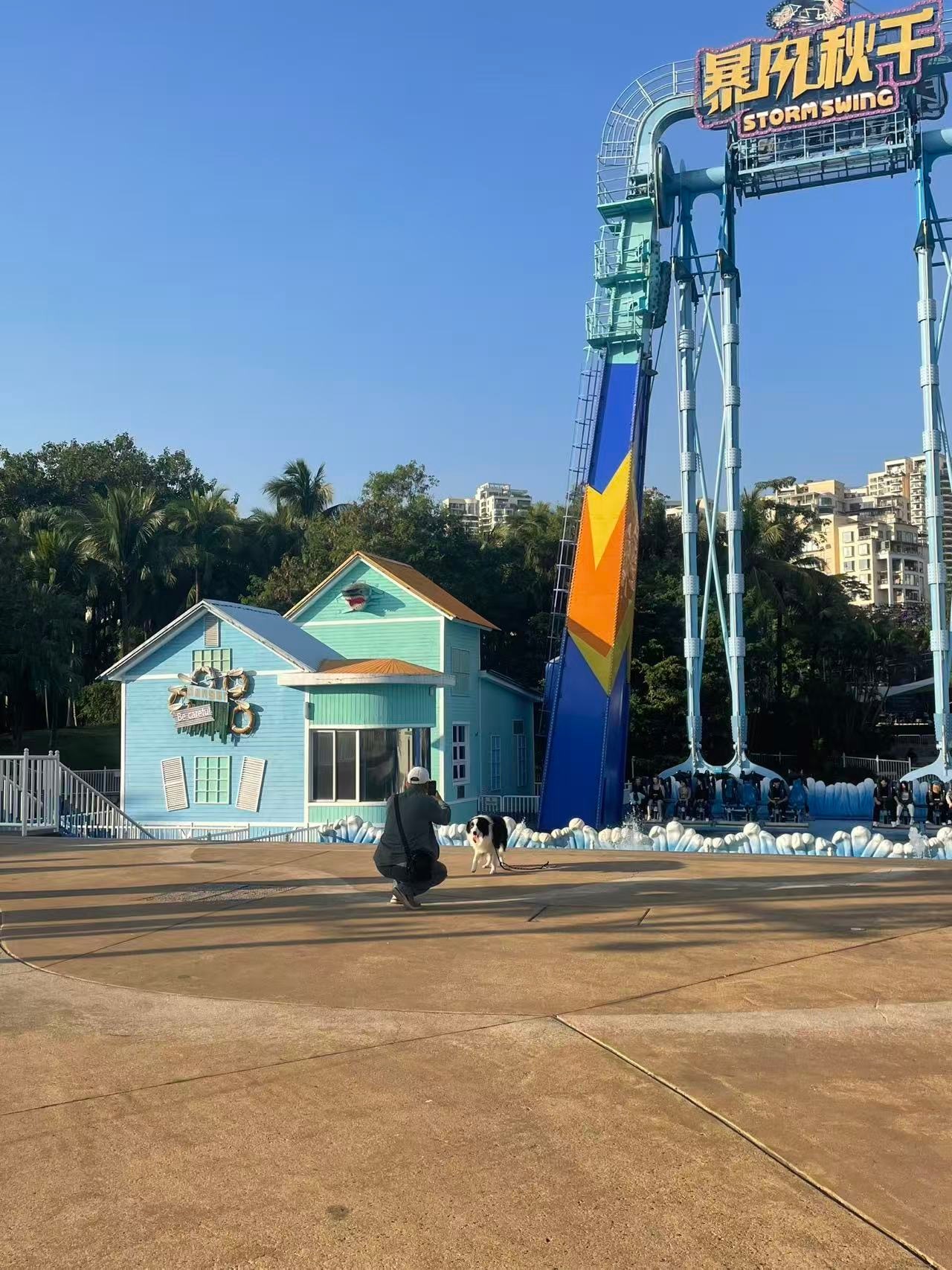 “毛孩子”家长为狗狗和游乐设施上的游客合影