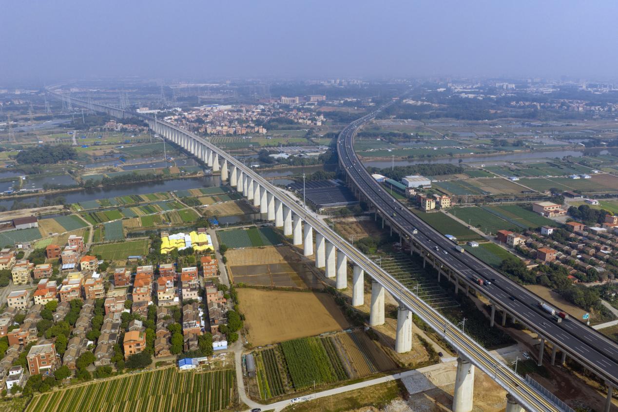 图为:延绵的广湛高铁轨道与村居、田园相映成景。